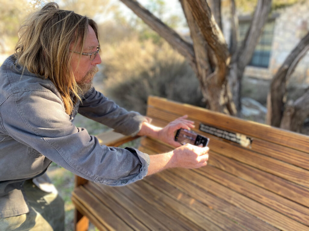 Jack Hudson, owner of Quality Patio Furniture, attaching an engraved memorial plaque onto a Low Back Couch