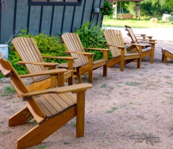 Quality Patio Furniture Curved Back Adirondack Chairs Handcrafted Jack Hudson (830) 367-3848 Curved Back Adirondack Chairs arranged in front of the sales office at Quality Patio Furniture Handcrafted by Jack Hudson (830) 367-3848