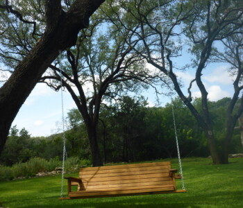 Quality Patio Furniture...Letting the world go by in a 6 ft. Low Back Porch Swing Handcrafted by Jack Hudson (830) 367-3848 6 ft. Low Back Porch Swing hanging from large tree over green grass Quality Patio Furniture Handcrafted by Jack Hudson (830) 367-3848