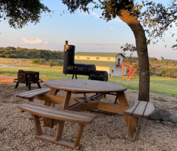 Quality Patio Furniture Round Picnic Table with Attached Benches under tree near BBQ pit Handcrafted by Jack Hudson (830) 367-3848 Round Picnic Table with Attached Benches under tree near BBQ pit Quality Patio Furniture Handcrafted by Jack Hudson (830) 367-3848